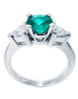 A round emerald and trillion side diamonds ring in 18k white gold, on a lateral top and gallery view.