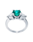 14K white gold ring with a vibrant round emerald center stone and two trillion-cut side diamonds.