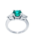 14K white gold ring with a vibrant round emerald center stone and two trillion-cut side diamonds.
