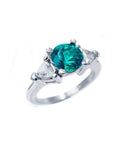 This natural emerald ring round cut with trillion side diamonds displays its top and right-side profile.