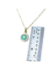 14K yellow gold minimalist necklace with a round-cut Colombian emerald and diamond halo, shown with a ruler.