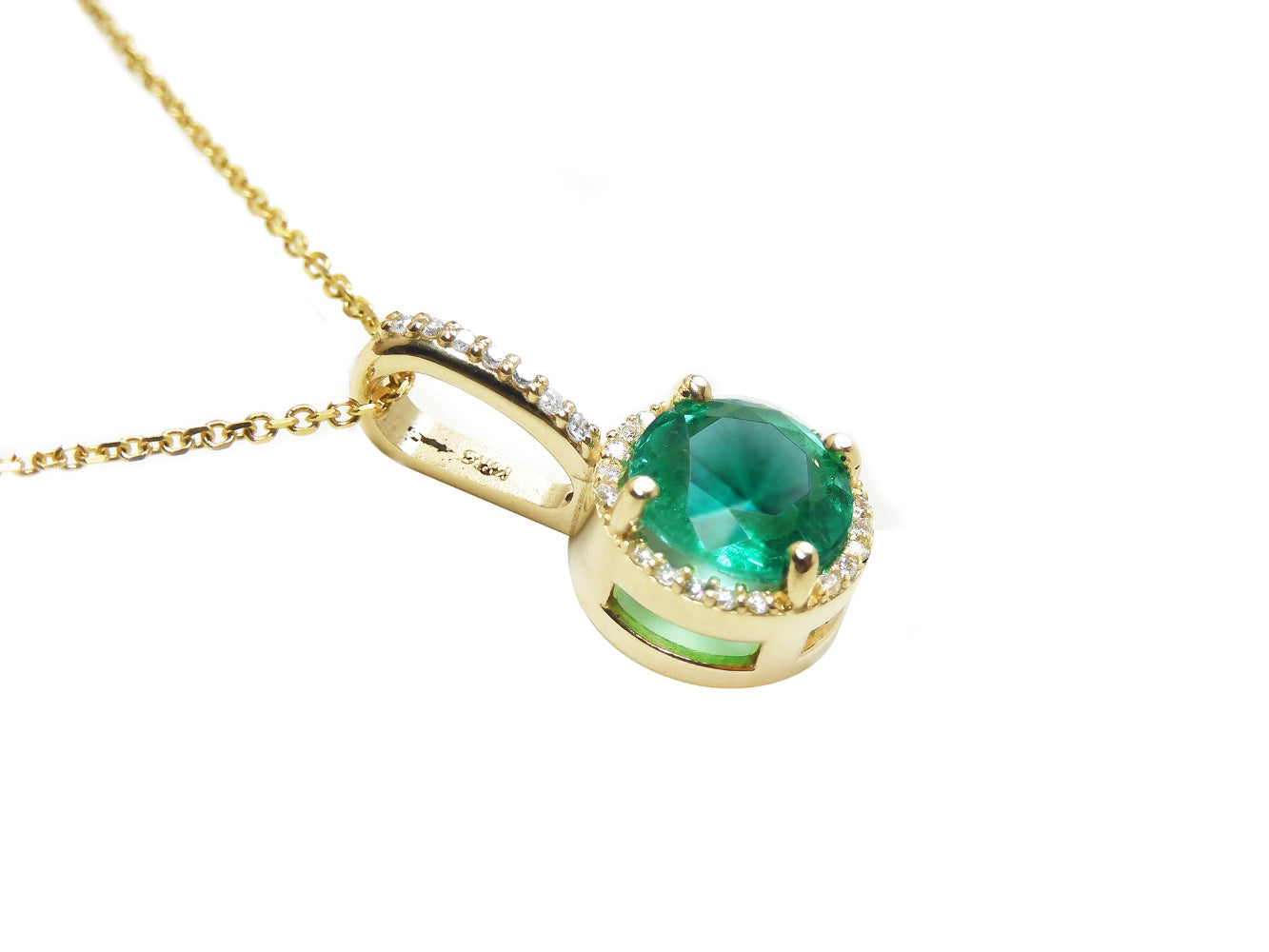 A yellow gold round cut natural colombian emerald halo diamond d
showing the top and gallery right profile side.