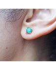 Round 1.09 ct. natural Colombian emerald stud earring in 14K gold basket setting on an ear.