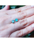 1.09 ct. natural Colombian emerald stud earrings in 14K gold basket settings with push backs, displayed on a hand.