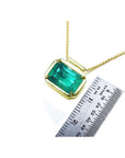 Women's Emerald solitaire necklace east west orientation rectangular prong set in a handmade setting in 18k yellow gold