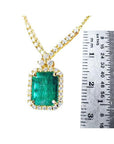 3.43 ct emerald halo necklace with natural diamonds on a 14K yellow gold chain, shown next to a ruler.