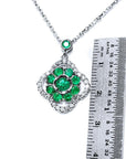 Green, emerald cluster pendant necklace 4-leaf clover design accented by natural diamonds with a ruler for scale on a white background