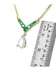 14K gold necklace with pear-cut diamond and seven round emeralds, shown with ruler for scale.