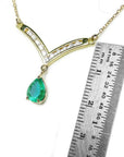 1.01 carat pear cut emerald necklace with accent diamonds on a 14K yellow gold V-chevron.