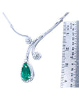 Pear cut 2.26ct natural emerald necklace in 18K white gold with diamond halo and accents, next to a ruler.