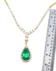 next to a ruler sizer of a genuine emerald necklace pear cut crafted in 18k yellow gold, halo diamond