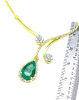 18k yellow gold necklace with a natural Colombian emerald teardrop pendant next to a ruler for scale on a white background