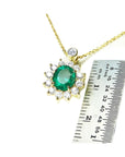 Oval cut emerald and natural diamond cluster necklace in 14K yellow gold, shown with a ruler for scale.