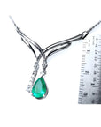 14K white gold necklace with a pear-shaped emerald and diamond chevron design, shown with a ruler.