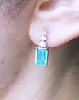 Close-up of an ear wearing a natural emerald-cut earring with a diamond accent.