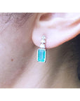 Close-up of an ear wearing a natural emerald-cut earring with a diamond accent.