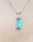 A natural emerald pendant on a white gold chain dangling of a woman's neck