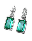 Pair of earrings with natural emeralds and top diamond accents on a left side profile
