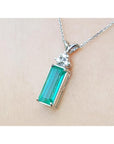 Emerald rectangular gemstone pendant with white gold chain on beige background