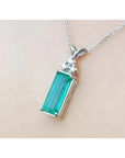 Emerald pendant with accent diamonds in 14K white gold on a delicate chain.