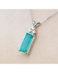 Emerald pendant with accent diamonds in 14K white gold on a delicate chain.