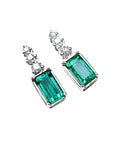 14K white gold dangle earrings with rectangular medium bluish-green emeralds and diamond accents.