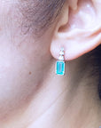 Close-up of an ear wearing a natural emerald-cut earring.