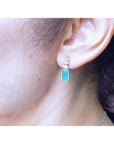 Close-up of an ear wearing a natural emerald-cut earring.