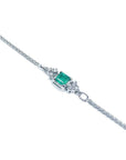 14K white gold bracelet with a central emerald-cut Colombian emerald and diamond accents.