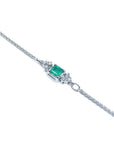 14K white gold bracelet with a central emerald-cut Colombian emerald and diamond accents.