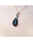 Teardrop Welo black opal pendant with red-orange and blue-green flashes on a 14K yellow gold chain.