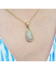 Opal pendant necklace on a person wearing a blue and white striped top.