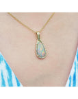 Opal pendant necklace on a person wearing a blue and white striped top.