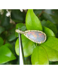 4.30 ct Australian opal pendant with fiery red-orange flashes, halo diamonds, 18K yellow gold, on green leaves.