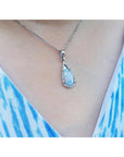 Teardrop-shaped solid opal pendant necklace on a person wearing a blue and white patterned top.