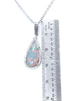 A natural Australian pear shaped opal pendant necklace with a ruler for scale on a white background.