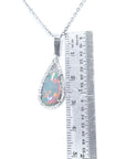 A natural Australian pear shaped opal pendant necklace with a ruler for scale on a white background.