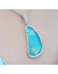 Australian opal pendant with blue-green play of color, halo diamonds, and 18K white gold chain.