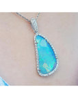 Australian opal pendant with blue-green play of color, halo diamonds, and 18K white gold chain.
