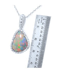 Opal pendant with gold chain next to a ruler on a white background