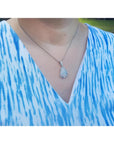 4.78 ct. solid Australian opal pendant with red-orange flashes, halo diamonds, and 18K white gold chain on a person.