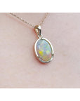 Opal pendant necklace on a light pink skin background.