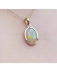 Oval white Australian opal pendant in 14k yellow gold on a delicate chain.