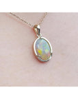 Oval white Australian opal pendant in 14k yellow gold on a delicate chain.