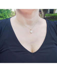 Woman wearing a 14k yellow gold necklace with a solid oval white Australian opal pendant.