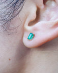 Close-up of an ear wearing natural emerald solitaire stud earring.