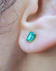 Close-up of an ear with a Colombian emerald solitaire stud earring.