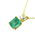Gold necklace with a natural colombian emerald pendant on a left-side position topside view.
