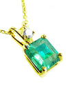 A yellow gold pendant with an emerald-cut natural colombian emerald displaying the topside.