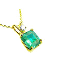 A yellow gold pendant with an emerald-cut natural colombian emerald displaying the topside.
